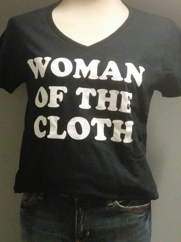 Picture of a black v-neck t-shirt with the words, "Woman of the cloth"